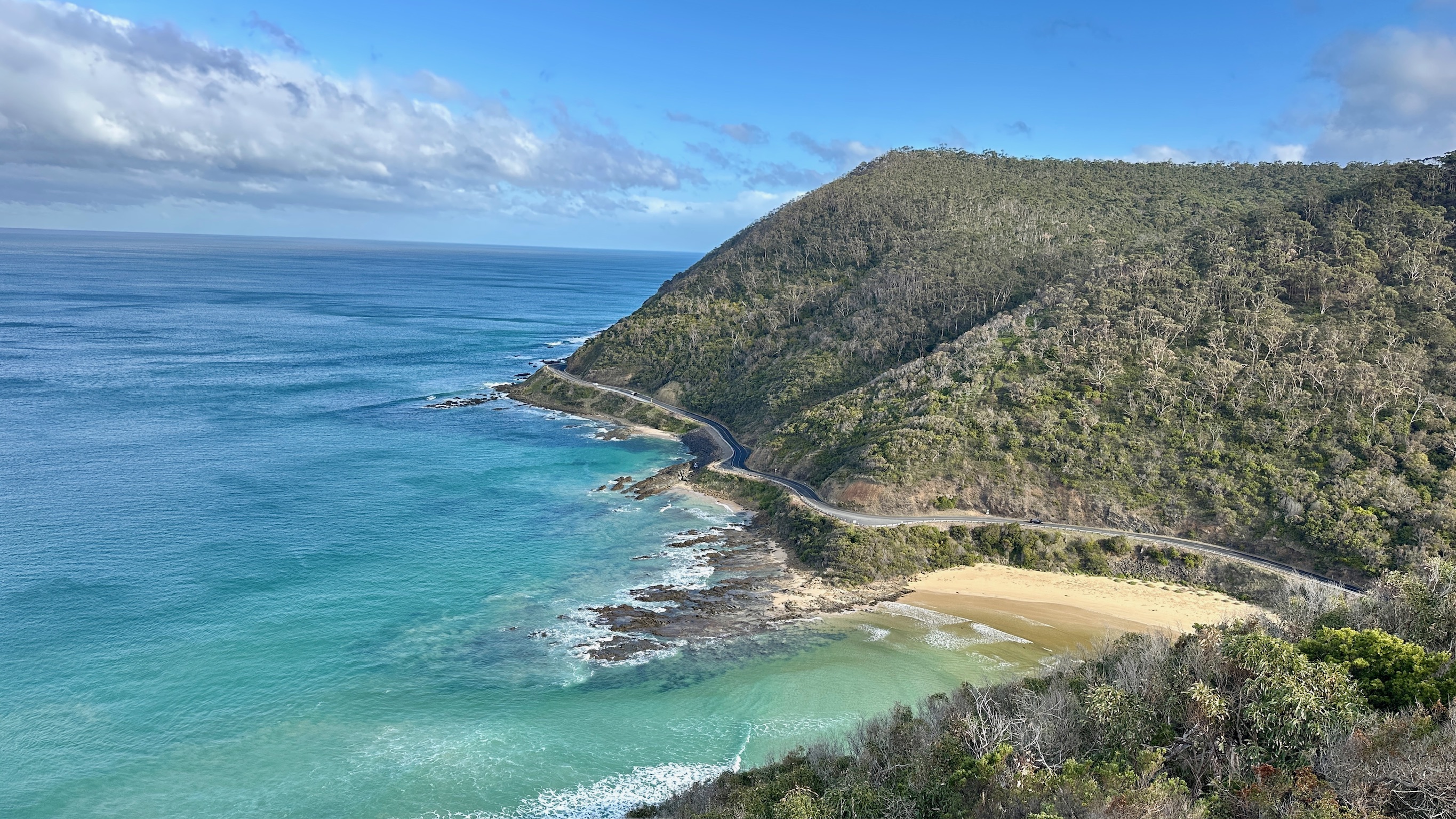 Great Ocean Road, Victoria — a sealed road curving along a forested headland above a turquoise bay